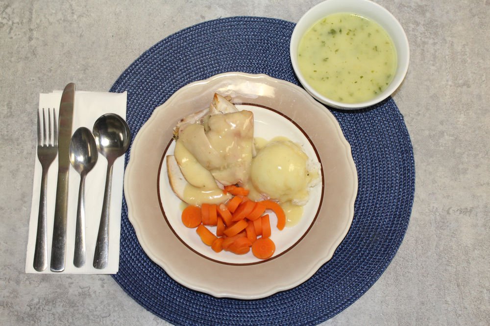 A plated lunch of chicken, mashed potatoes and carrots with a bowl of soup