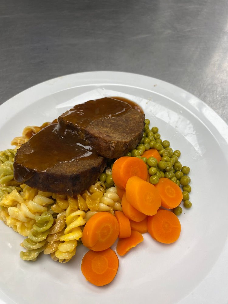 Meat loaf with gravy, pasta, peas and carrots