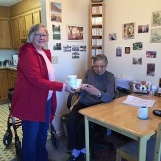 A volunteer delivering lunch to a client at her kitchen table
